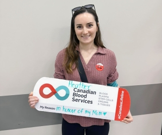 Blood donor with sign that says "in honour of my mom."