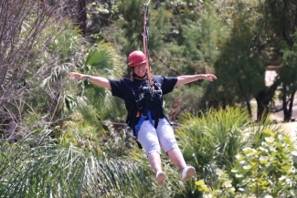 Woman rides a zip line through a forest