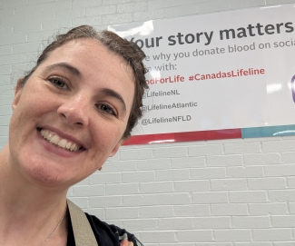 Blood donor smiling in front of Canadian Blood Services sign