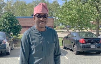 Akintunde Adeniyi posing at a car park in his traditional Yoruba attire.