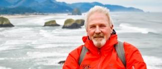 Image of plasma recipient Kirby Graeme standing outside in front of body of water and rocks.