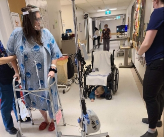 Woman with walker and face shield in hospital hallway