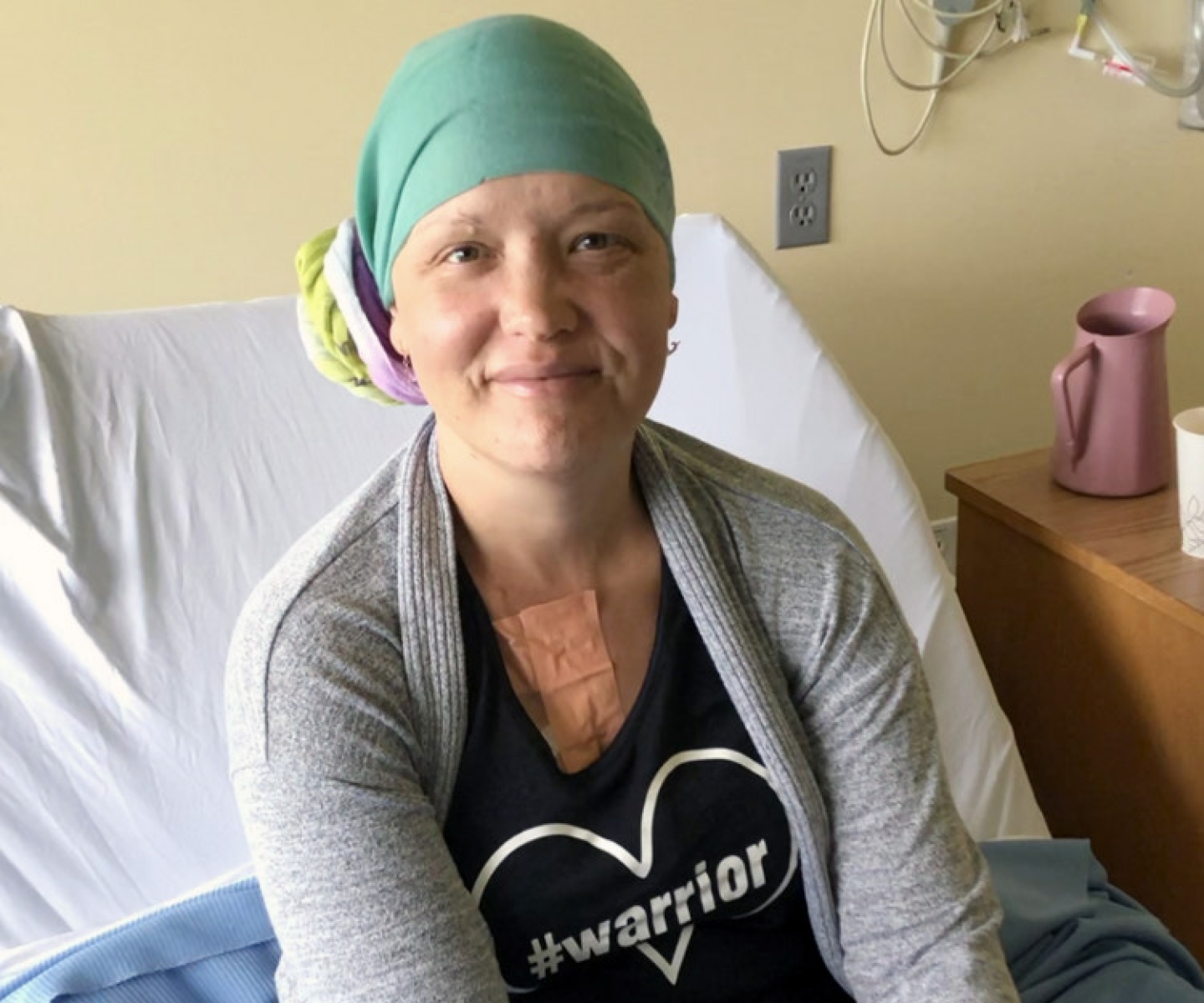 Ovarian cancer patient with T-shirt that says "Warrior" sitting on hospital bed