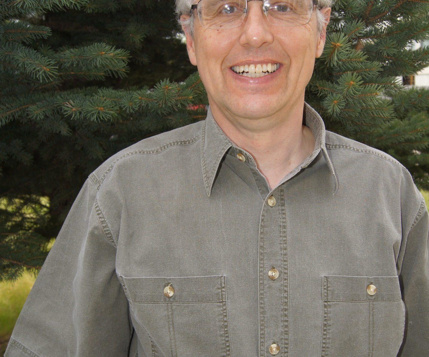 Man in short sleeved shirt poses for photo