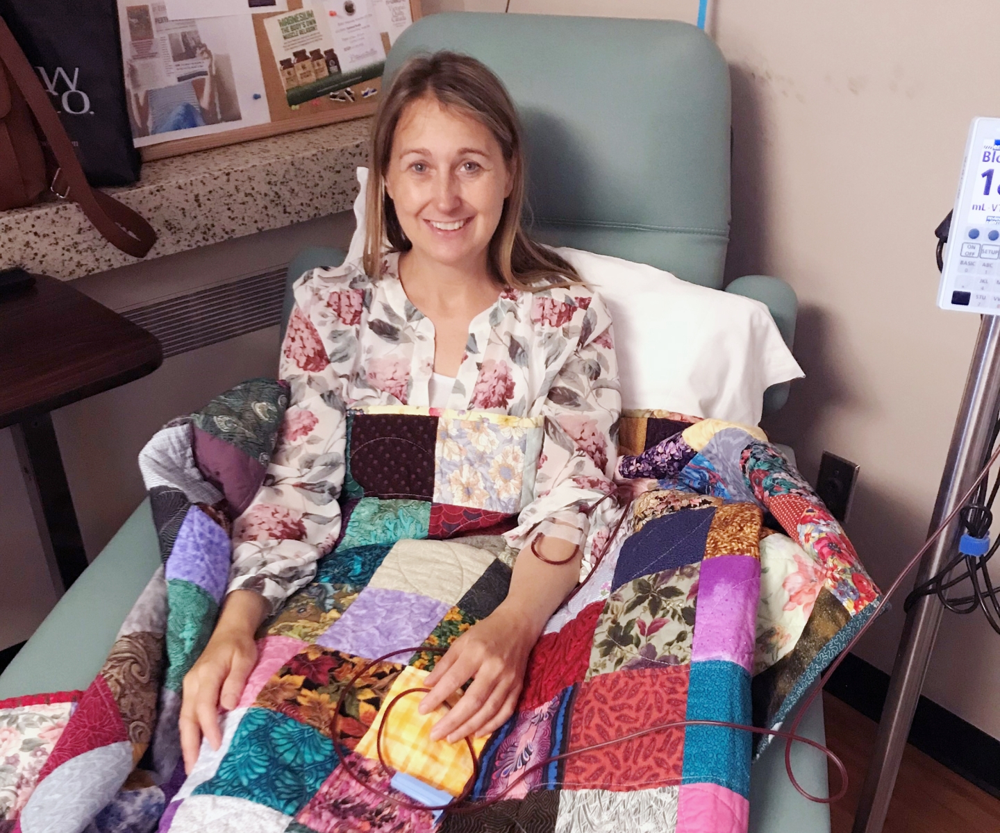 Woman covered by patterned quilt receiving blood