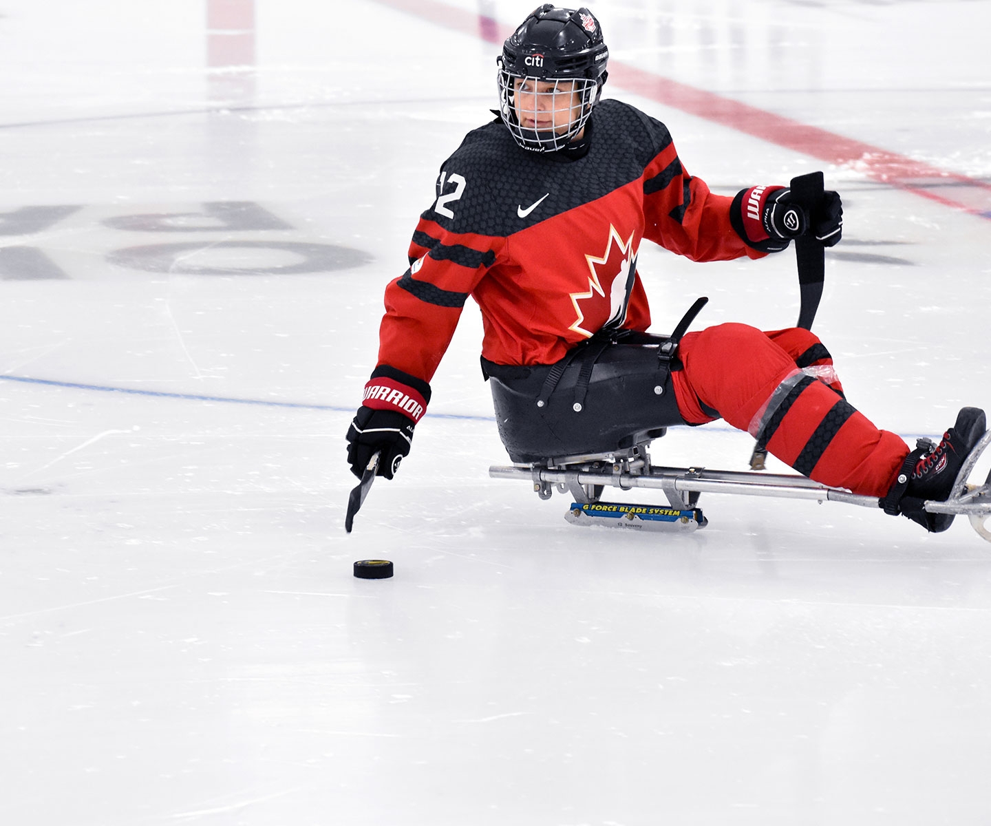 Para-hockey player moving stick toward puck on the ice