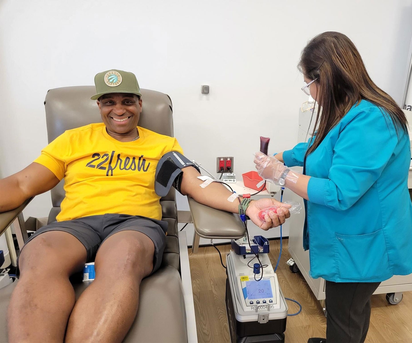 Rare blood donor sitting in chair as phlebotomist draws his blood.