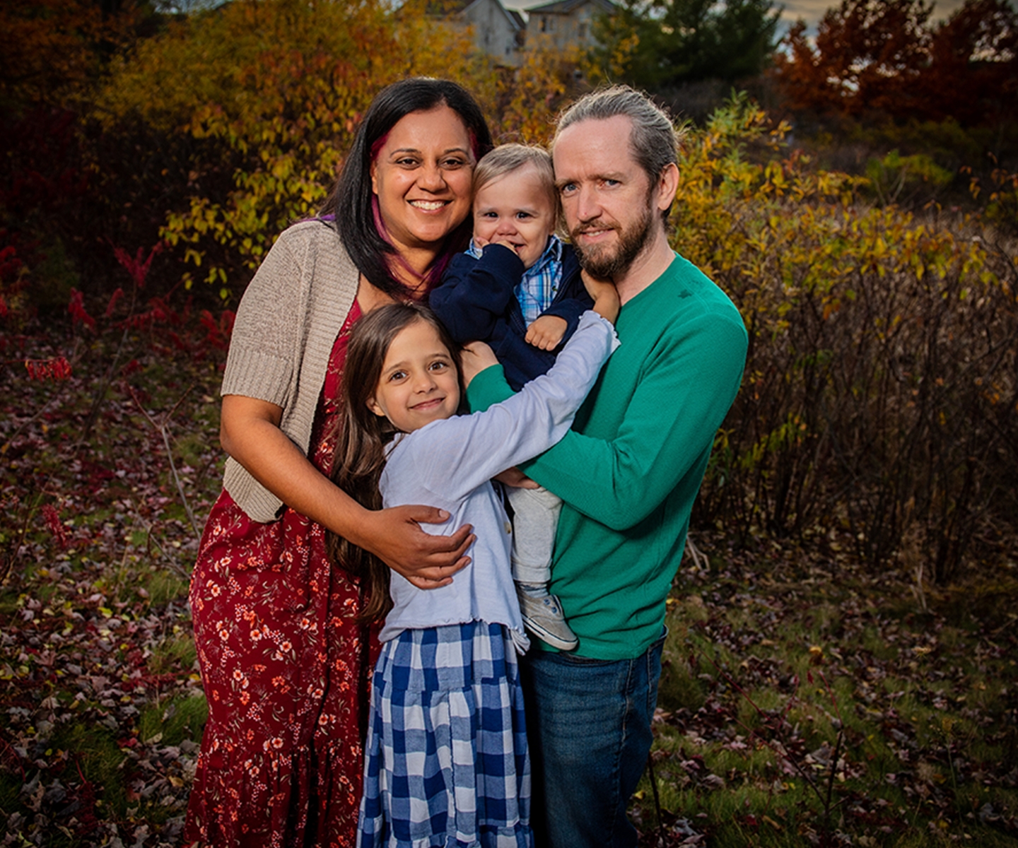 family of four hugging outdoors 