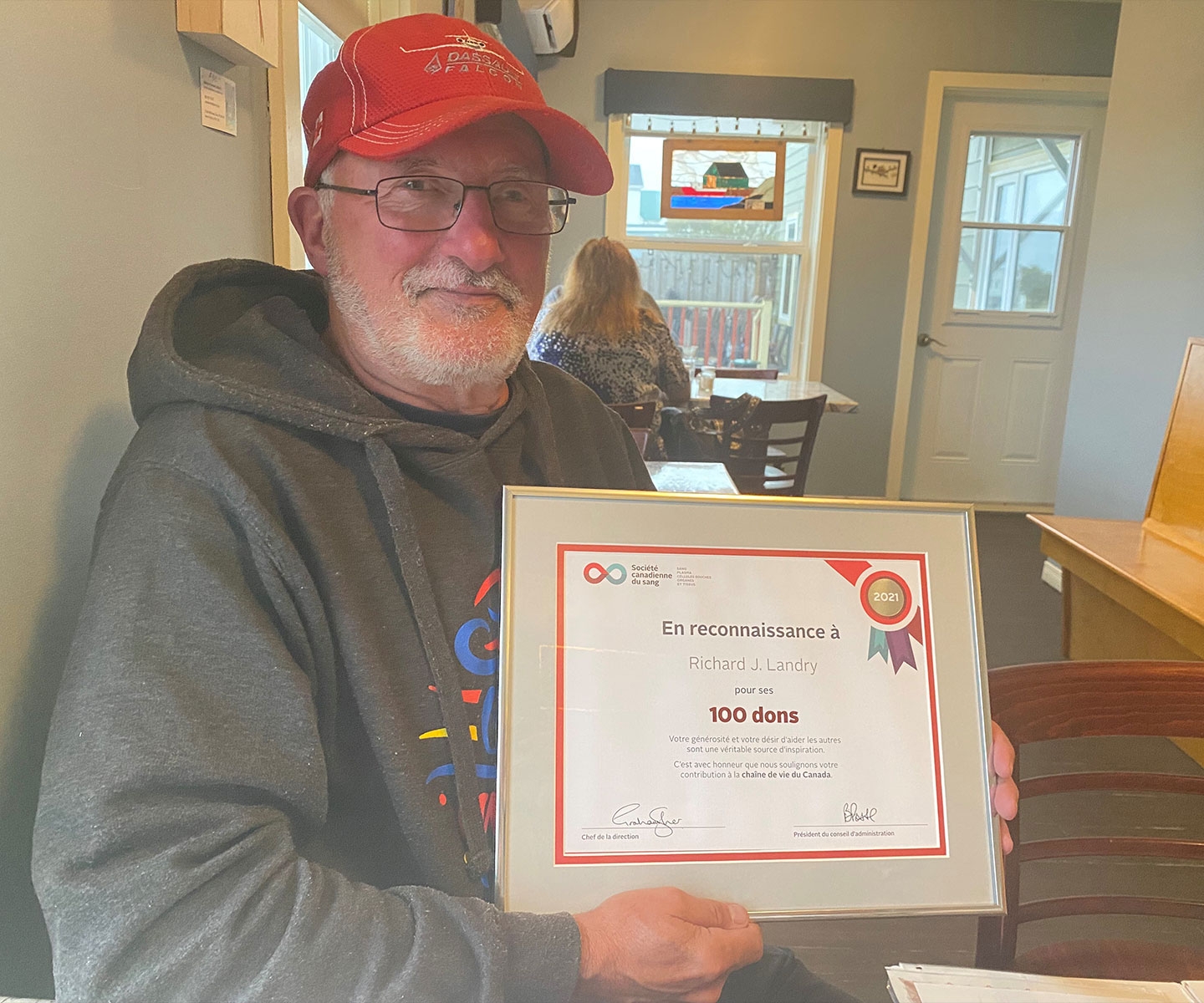 Blood donor holding certificate for 100 donations