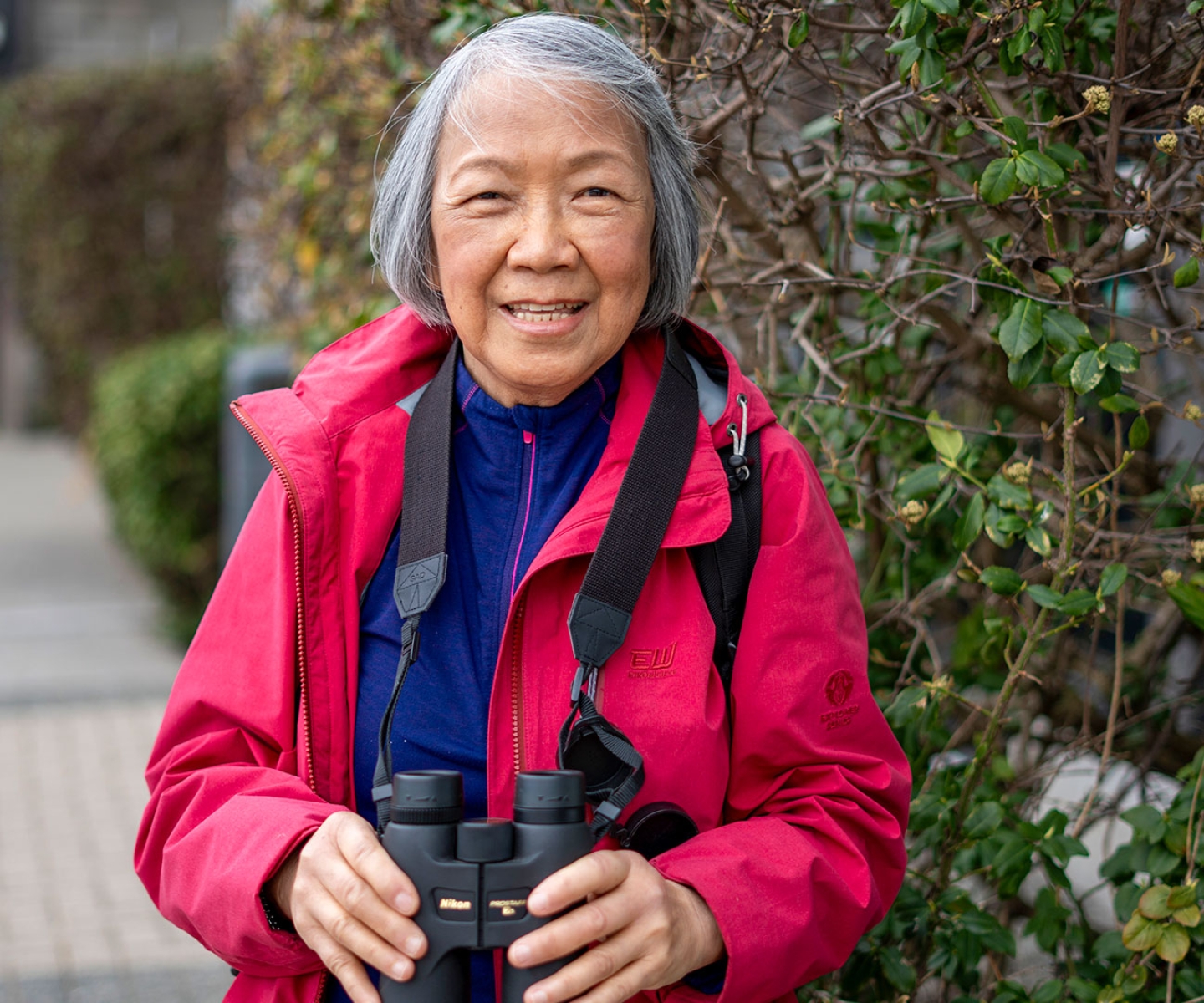 Blood recipient wearing pink jacket holding binoculars