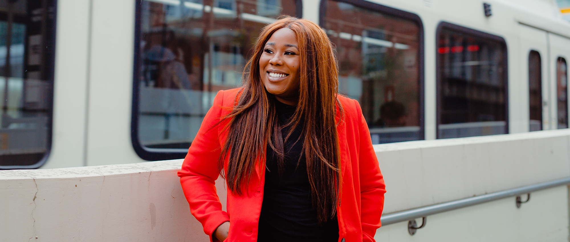 Stem cell recipient Ufuoma Muwhen smiles in front of a train.   