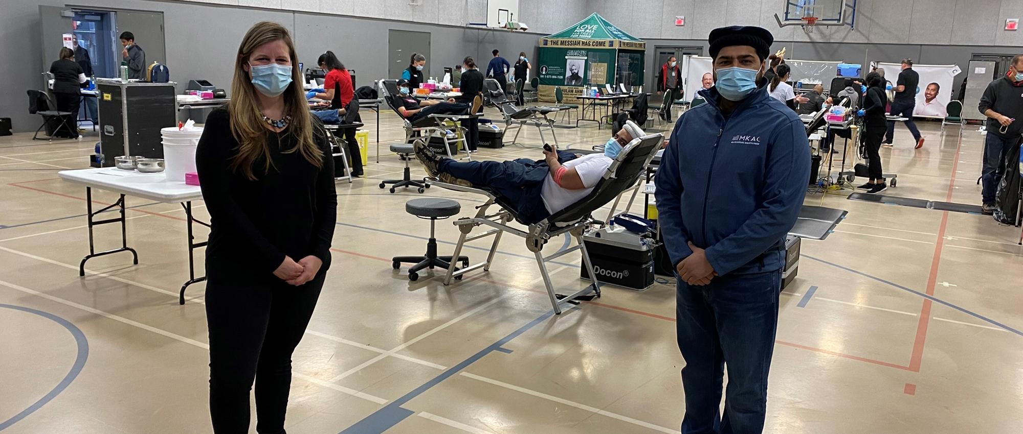 Staff in a gym converted to a blood collection centre with donors in the background