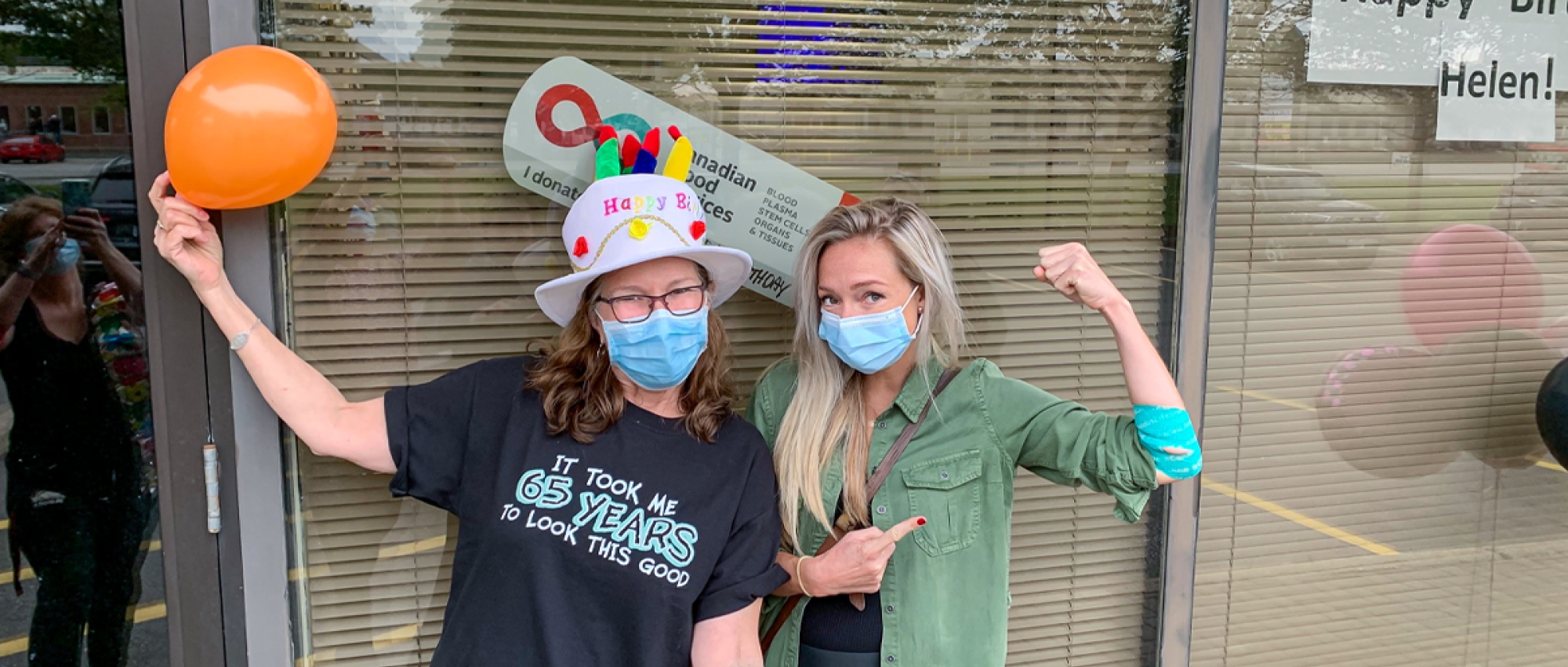 Featured image of Aaryn Coutts poses with Helen Raymond after donating blood at Helen's blood donor event in front of a window.