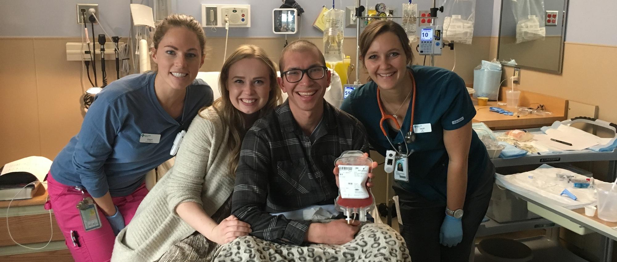 Mike Wark, who had a stem cell transplant, holds a bag of stem cells while surrounded by his wife and hospital staff