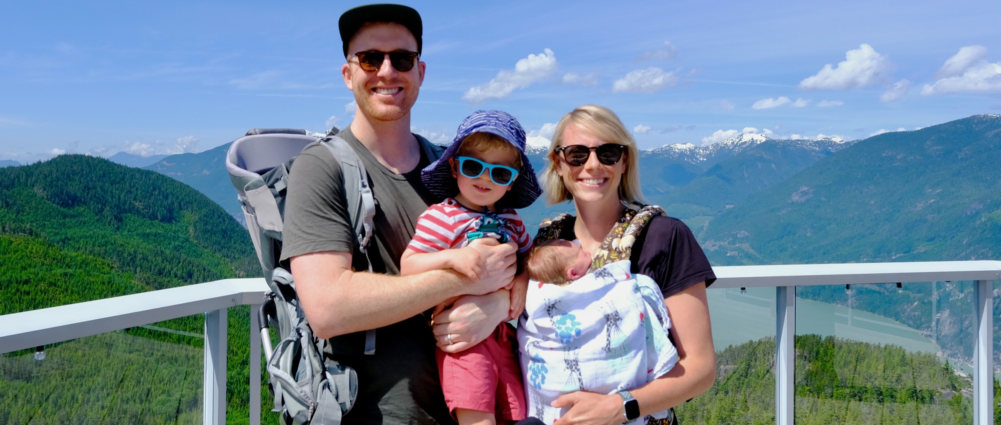 Dressed in casual outfits, Tyler and Rebecca Munk hang out with their toddler and baby on a bridge in Squamish, B.C.