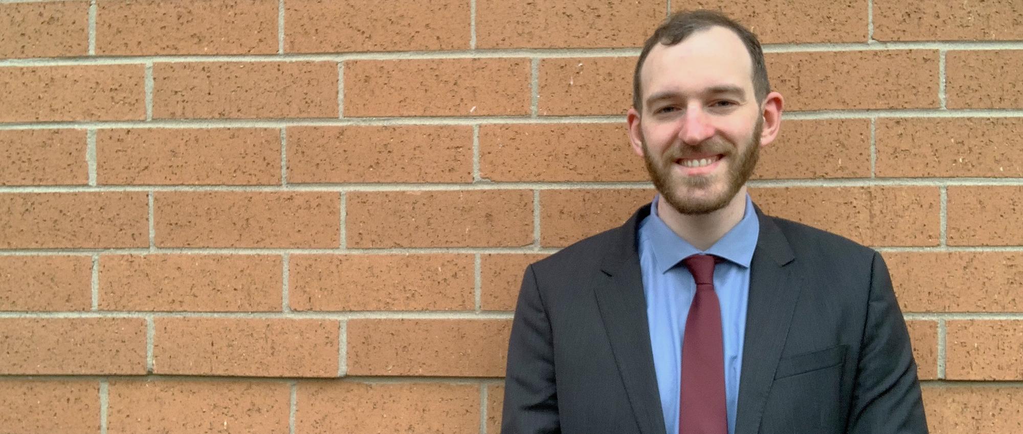 Dr. Warren Fingrut, who founded Stem Cell Club to recruit donors to Canadian Blood Services Stem Cell Registry and increase diversity of prospective donors, smiles while posing in front of a stone wall. 