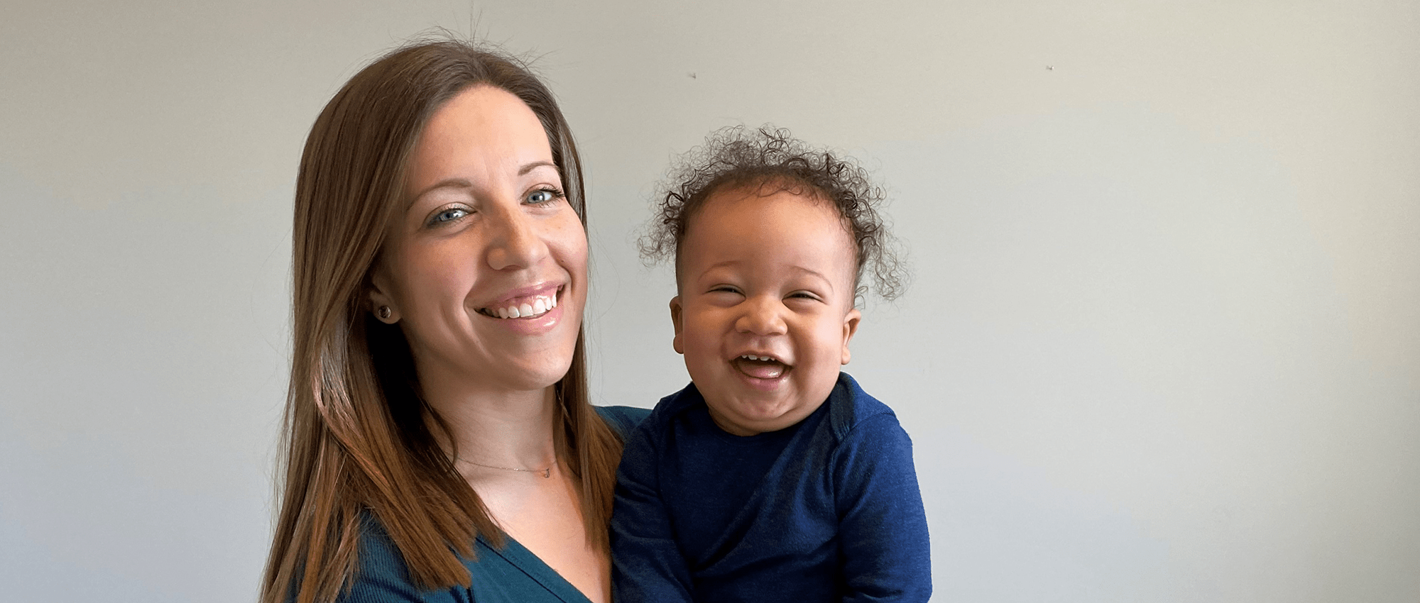 Laine Greenidge holds her smiling toddler in the nursery of their home. 