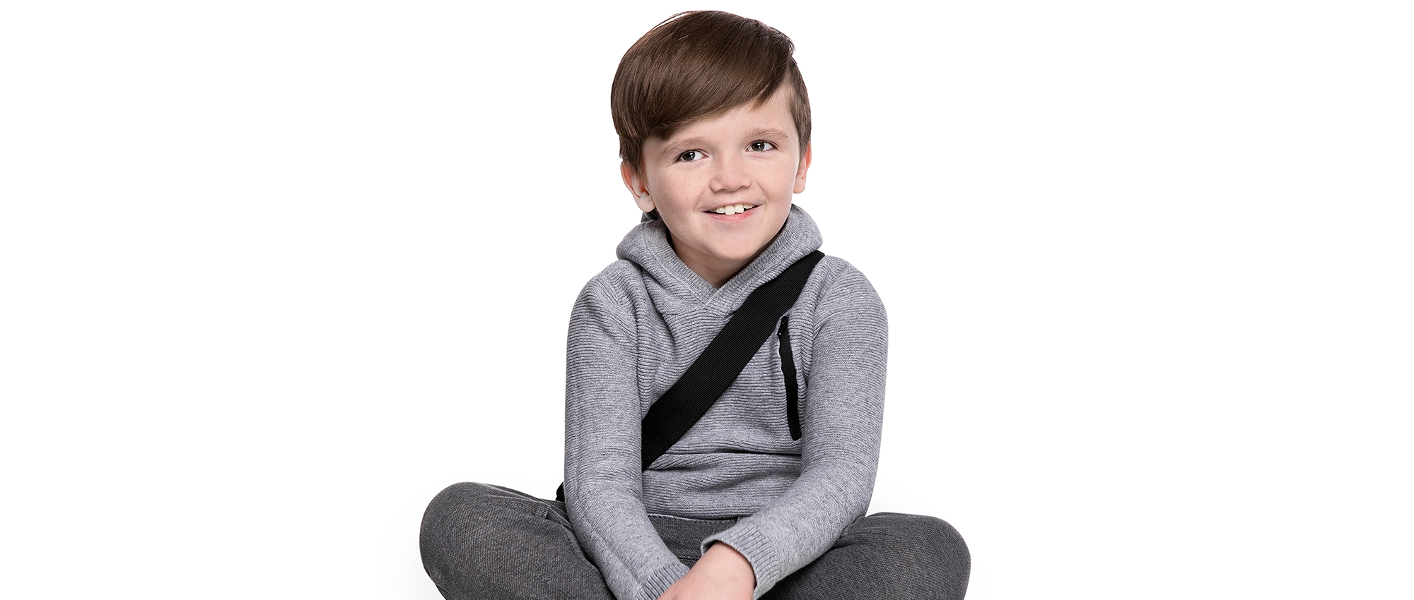 Young boy sits cross-legged, smiling