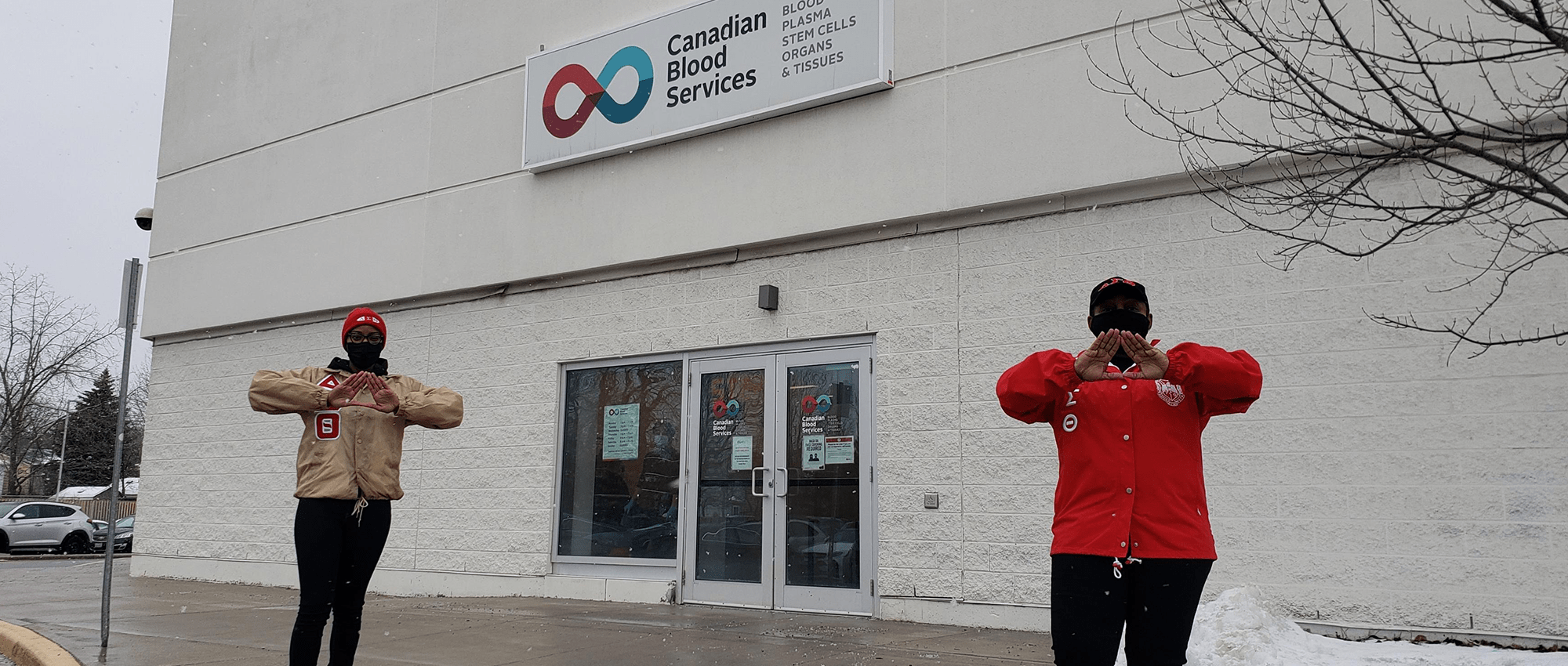 Two blood and stem cell advocates stand in front of a blood donor centre 