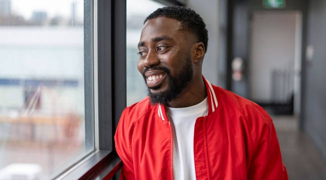 Man in red jacket smiling and looking through window