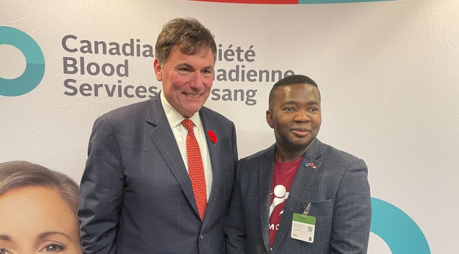 Minister Dominic LeBlanc and Jacob Marfo pose in front of a Canadian Blood Services backdrop