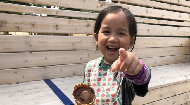  Child blood recipient holding ice cream, smiling and pointing at photographer