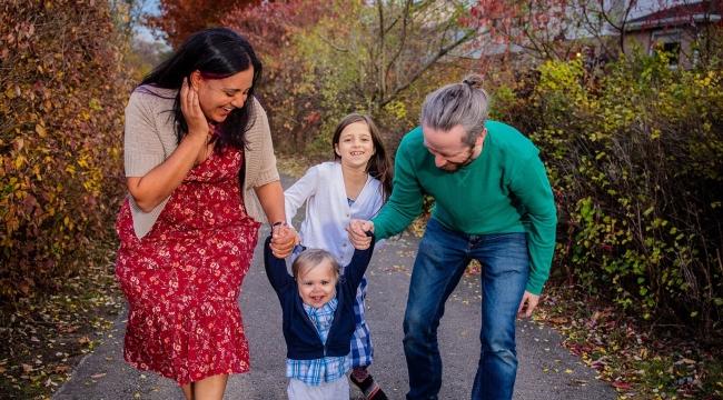 Un bébé ayant reçu des cellules souches de sang de cordon, en présence de sa mère, de son père et de sa sœur, marche dans un chemin, à l’extérieur