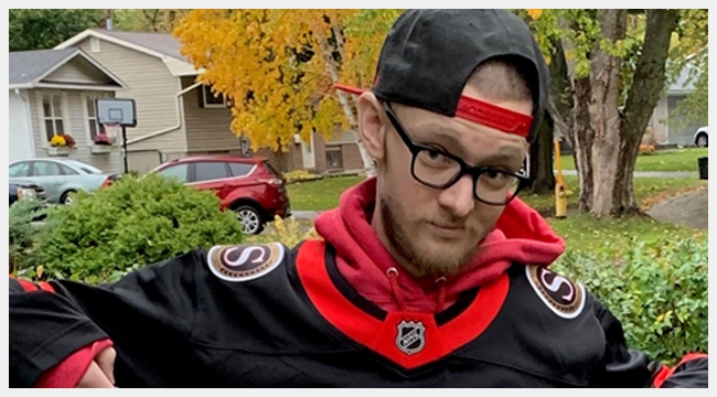 Image of Brian Fraser with black glasses wearing an Ottawa Senators jersey and a backwards cap.