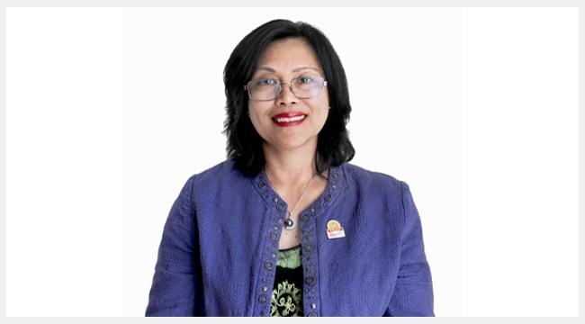 A Filipino woman, wearing a blue jacket with a Canadian Blood Services pin on her lapel.