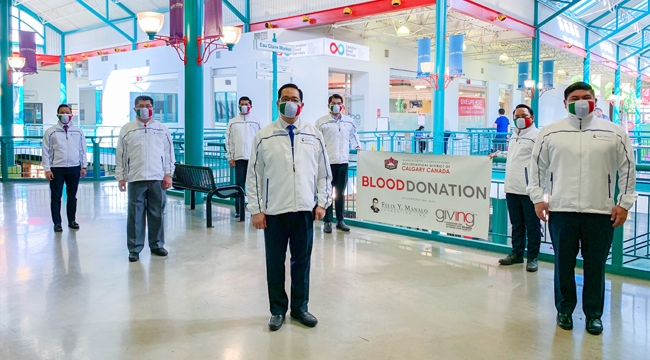 Members of Iglesia ni Cristo (Church of Christ) stand near a sign advertising a blood donation event in Calgary, Alta.