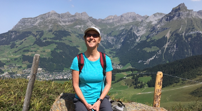 Margaret Lynch, who had a bone marrow transplant about 33 years ago, sits on a rock in front of The Alps in Switzerland.