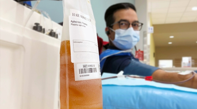 Ron Shivji looking at bag of plasma while donating plasma