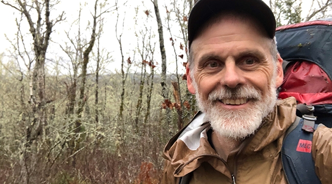 Jonathan Riley in the woods with a backpack on